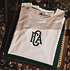 Detailaufnahme eines gefalteten, cremeweißen T-Shirts, das auf einem dunkelgrünen T-Shirt auf einem  (2)