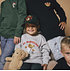 Ein Mädchen sitzt im grauen FCA-Teddy-Sweatshirt. Sie trägt eine Teddy Cap und hält einen Teddy (2)