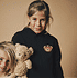 Kleines Mädchen trägt denFCA-Kinder Hoodie Teddy Schwarz vor einen Beigen Hintergrund (2)